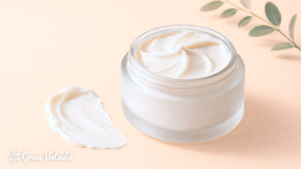 Frasco de vidro com creme facial caseiro de textura suave e uma amostra de produto espalhada ao lado.