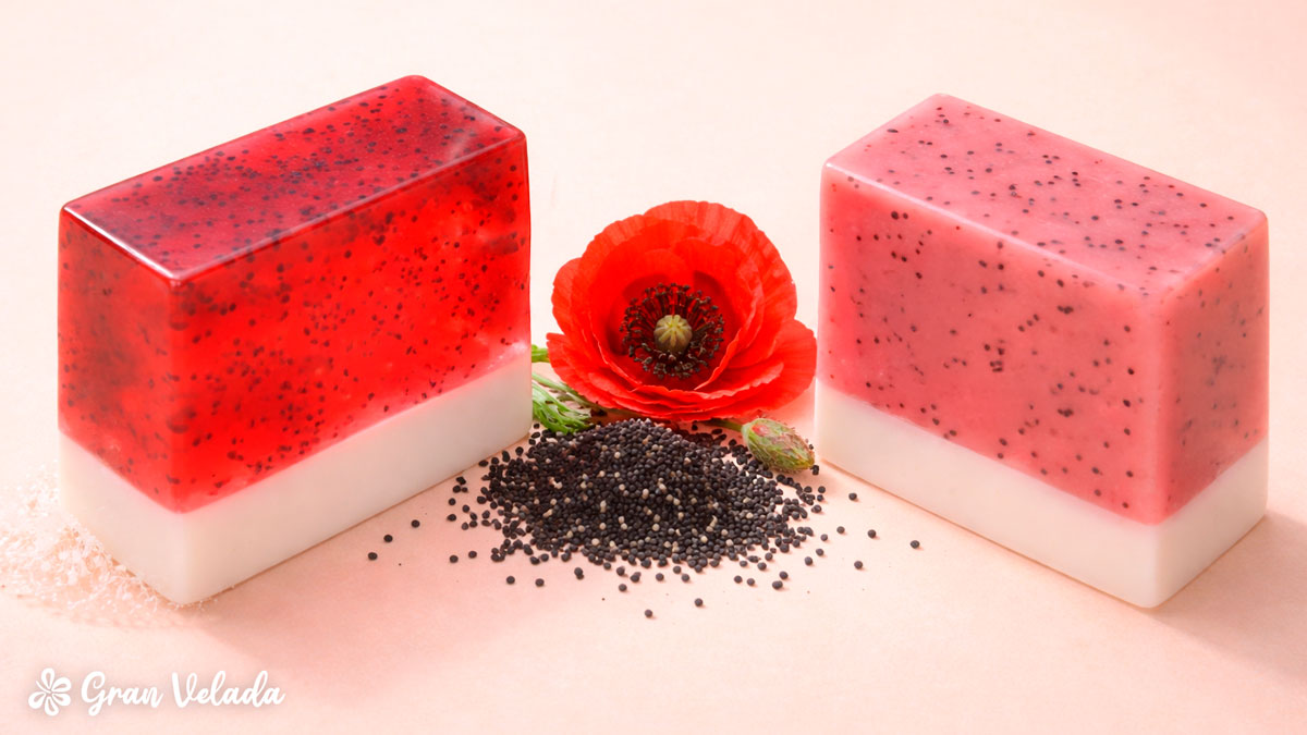 Duas barras de sabonete de glicerina vermelhas. Uma opaca e a outra transparente com sementes de papoila. No centro encontra-se uma papoila.