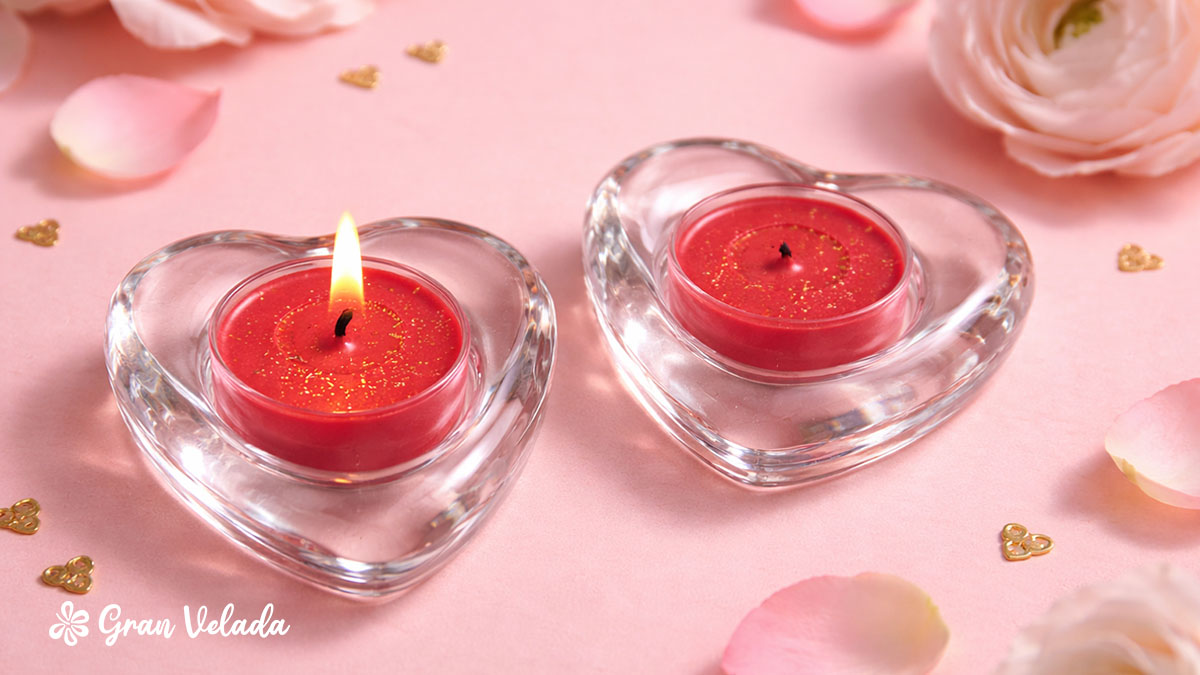 Duas velas de chá vermelhas com purpurina dourada colocadas em suportes de vidro em forma de coração.